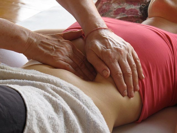maini de barbat care maseaza spatele unei persoane care are febra musculara