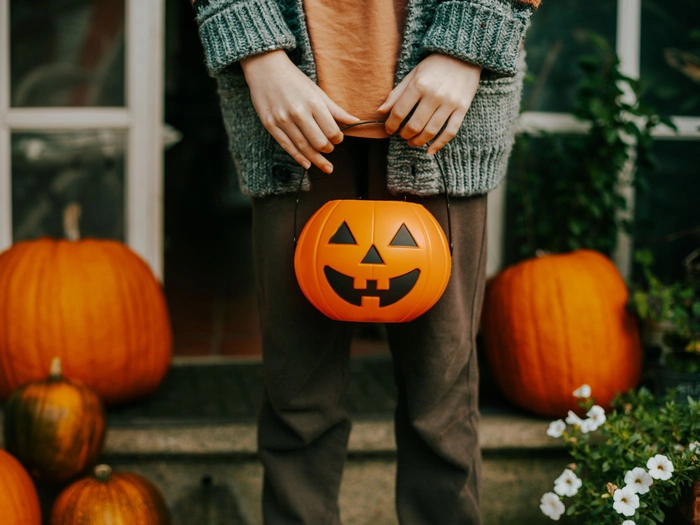 o persoana ce tine in mana o caldare in forma unui dovleac de Halloween