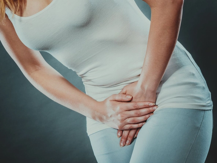 femeie care se tine de zona intima din cauza durerii provocata de infectia urinara