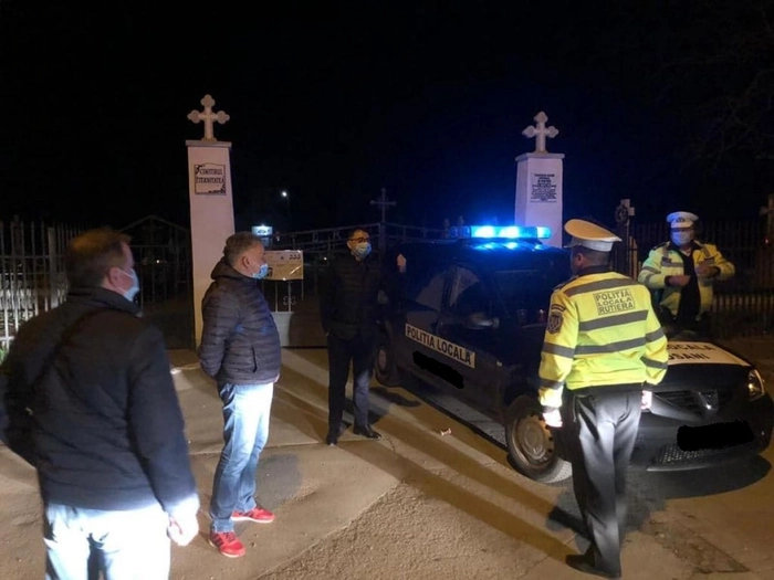  un echipaj de politie rutiera se afla in fata unui cimitir, pe timp de noapte