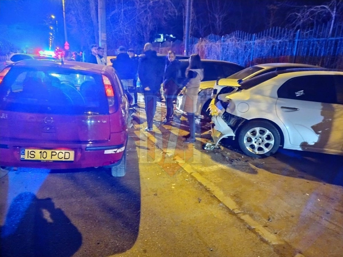 Mai multe persoane, pe strada, langa masini avariate