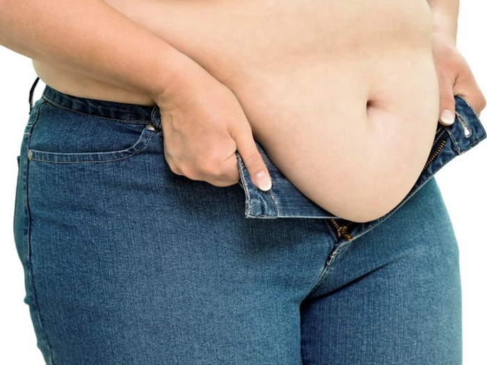 femeie care are exces de grasime pe burta si vrea sa se incheie la pantaloni