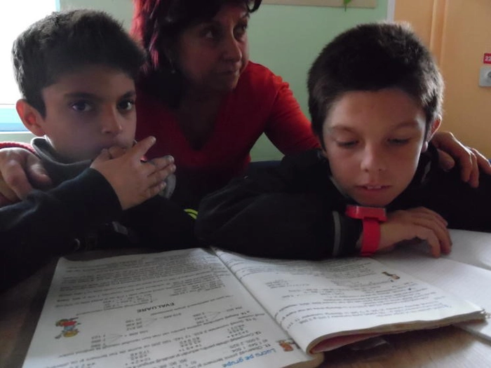  Copii și mama care se uita in manual scolar