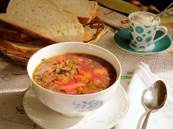 un bol cu ciorba de loboda langa mai multe ingrediente langa un bol cu felii de paine