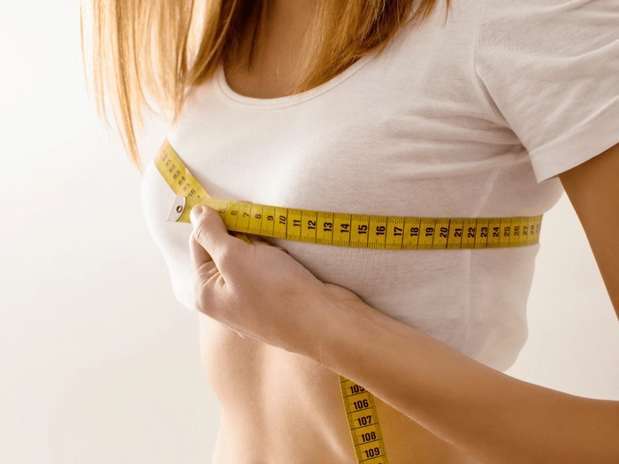 femeie care isi masoara cu un metru marimea sanilor