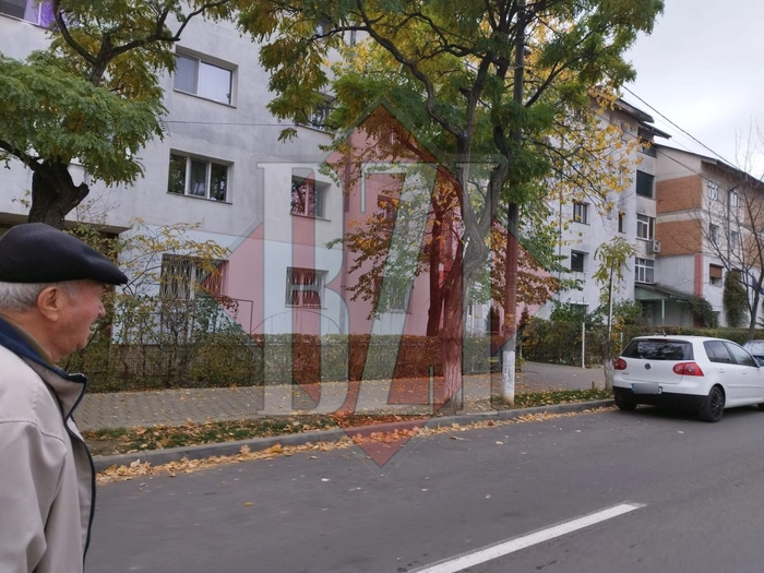 strada cu blocuri, masini si o persoana