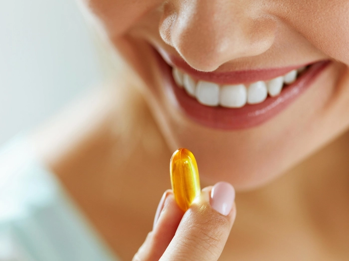 femeie care administreaza o capsula de omega 3