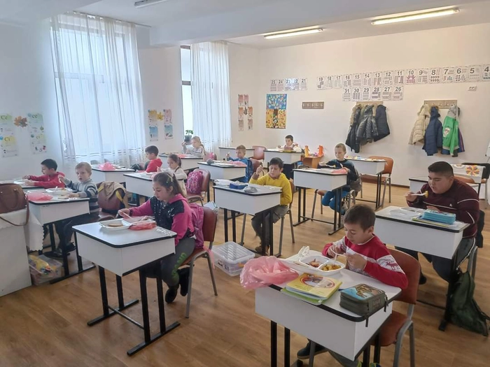 copii ce stau in banci si iau masa