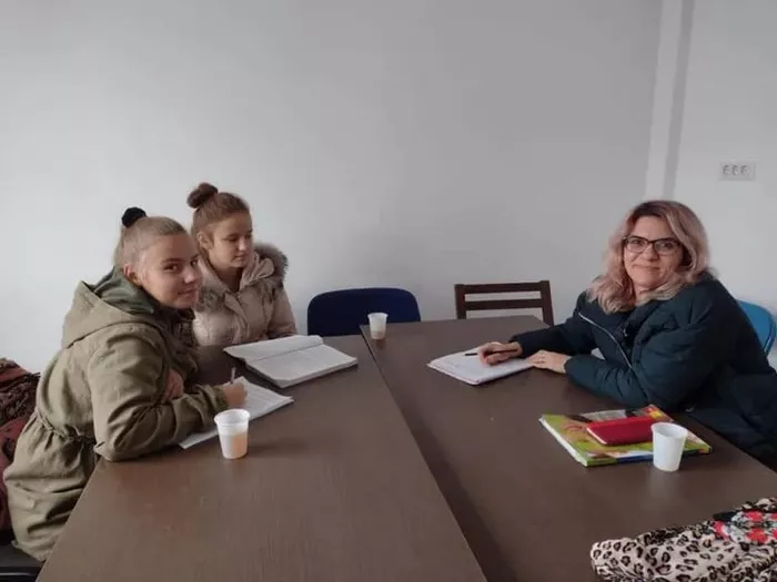 O poza cu profesoara si elevii la o masa