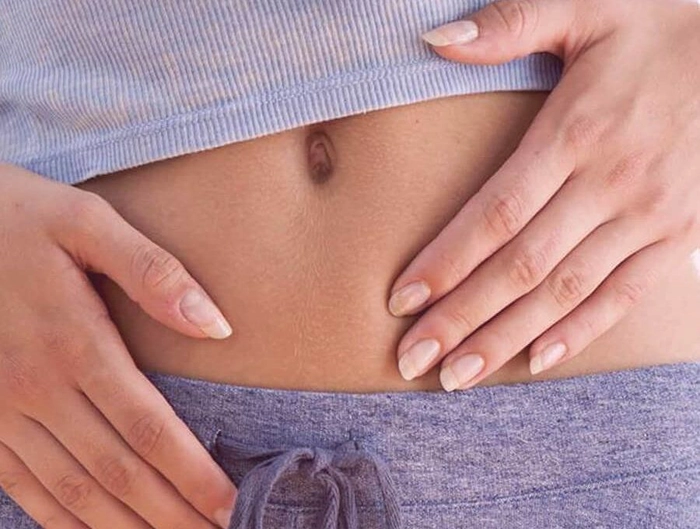 femeie care se tine de burta din cauza durerii provocate de chisturile ovariene