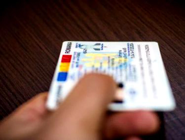 persoan[ care ține în mână o carte de identitate