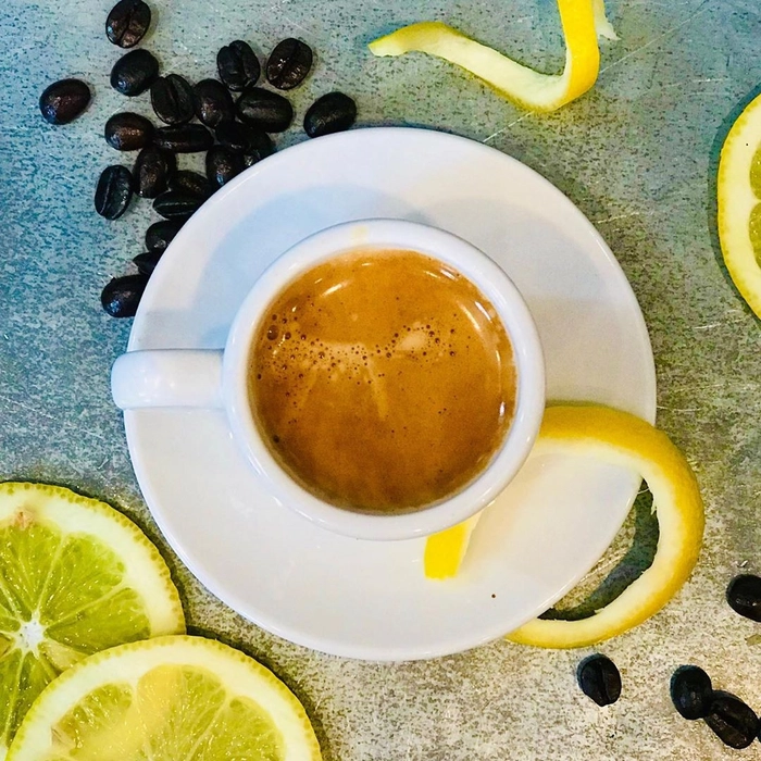 o cana de cafea langa mai multe felii de lamaie pe o masa
