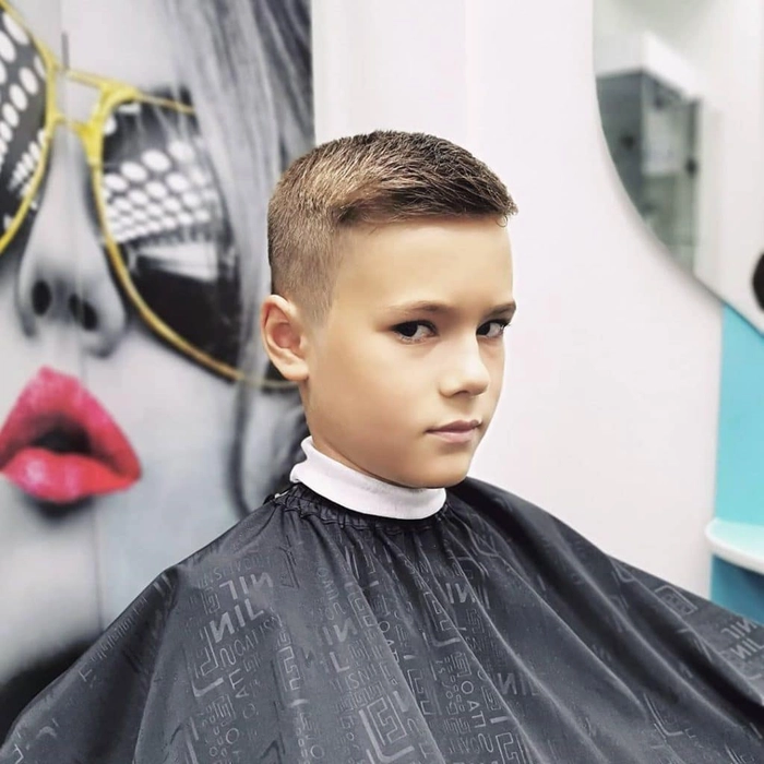 baiat pe un scaun la salon cu o noua tunsoare