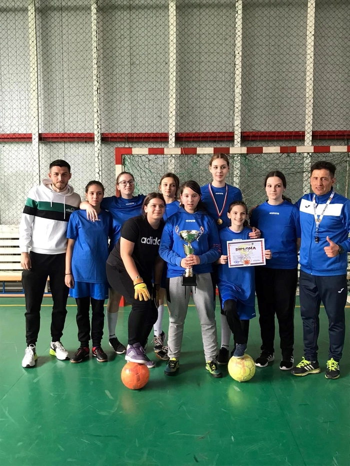 echipa sportiva alaturi de antrenori cu o cupa in mana