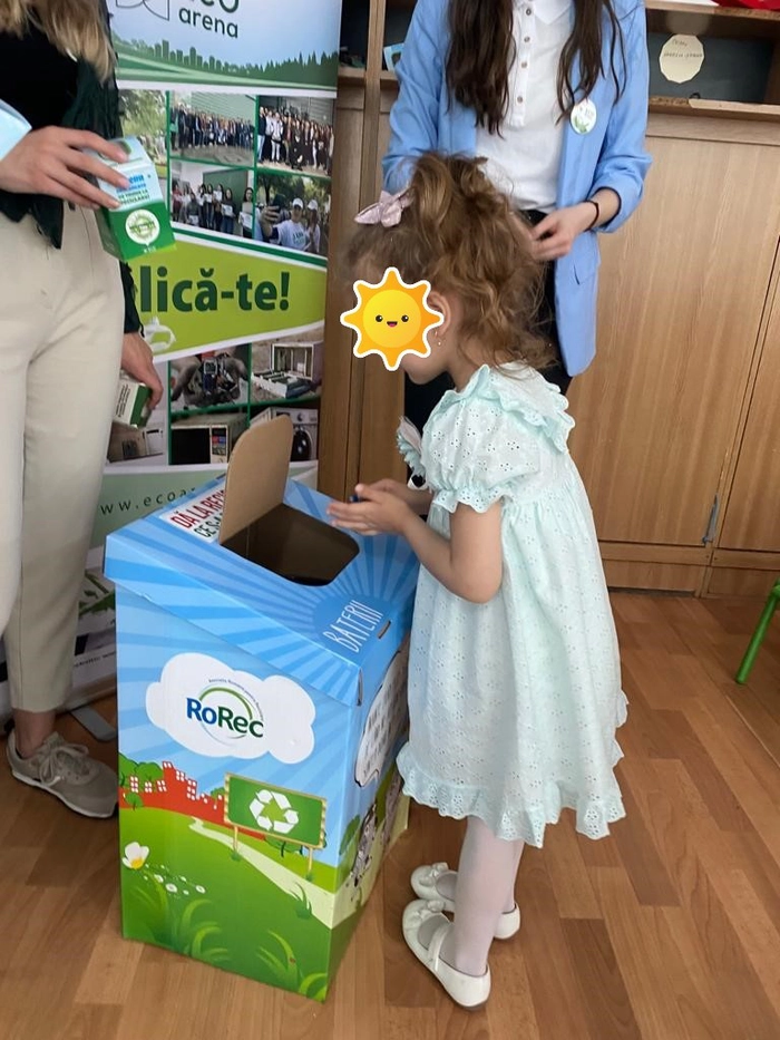 o fetita in fata unei urne de carton
