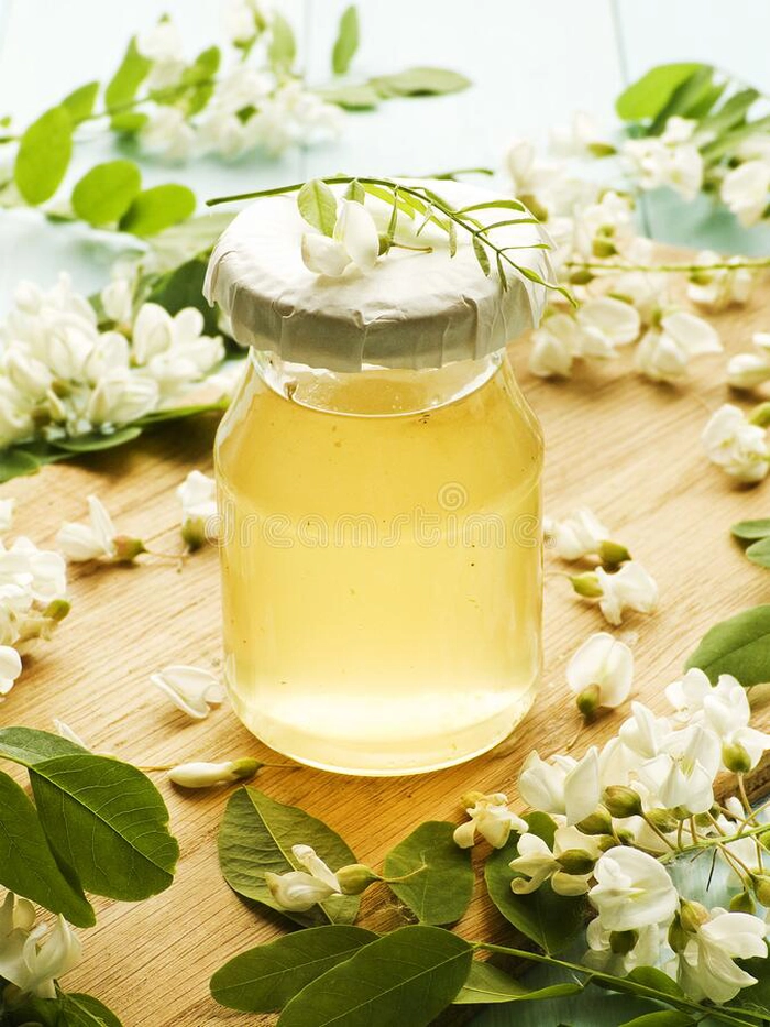 un borcan cu sirop de salcam pentru iarna inconjurat de mai multe flori