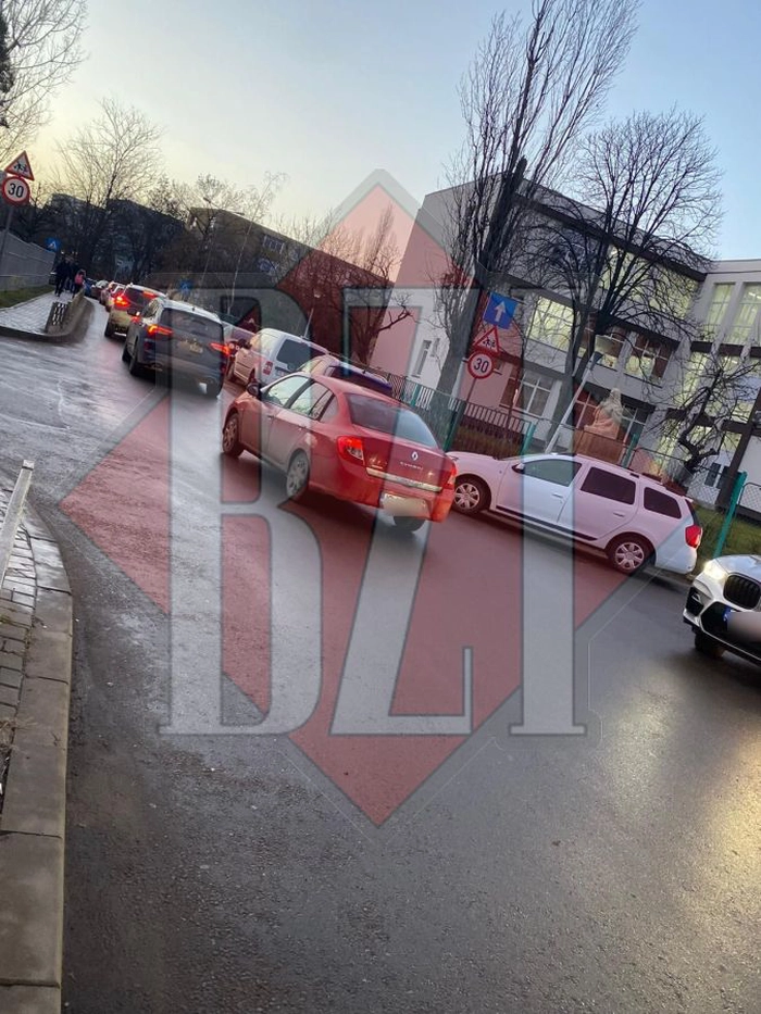 O strada plina cu masini cu parinti care isi lasa copiii la scoala