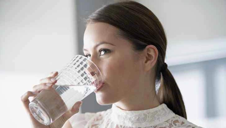 o femeie care bea un pahar cu apă