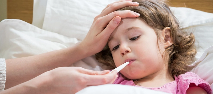 un copil care are un termometru în gură pentru că are febră