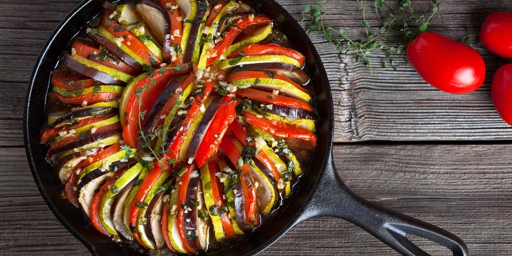 ratatouille intr-o tigaie langa mai multe ingrediente pe o masa