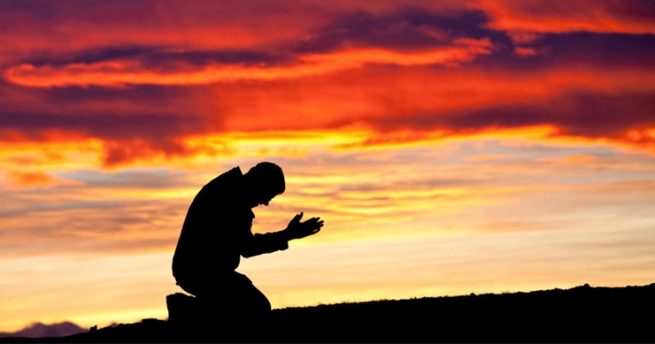 un bărbat care stă în genunchi și se roagă