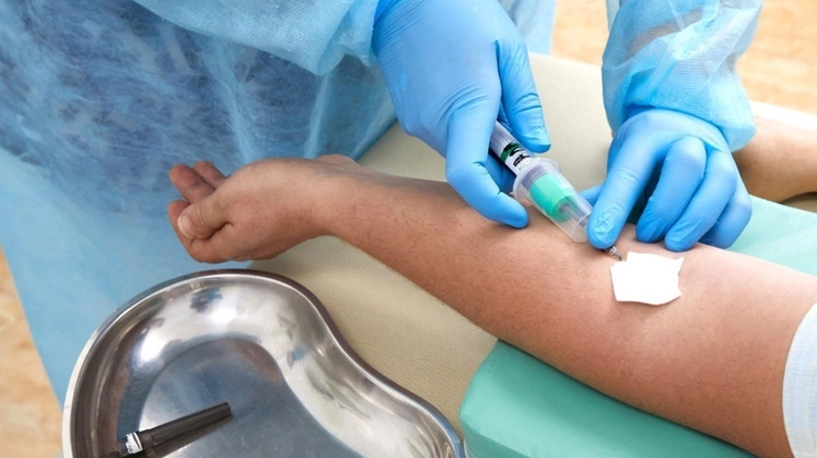 medic care preleva sange din vena unei persoane cu o seringa