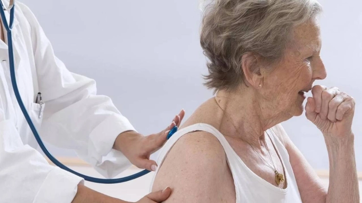 medic care asculta cu un stetoscop plamanii unei femei care tuseste