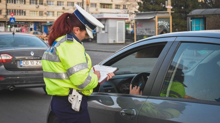  O femeie-politist scrie pe un clipboard langa o masina