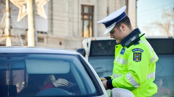 Un politist ce legitimeaza o femeie ce sta intr-o masina gri