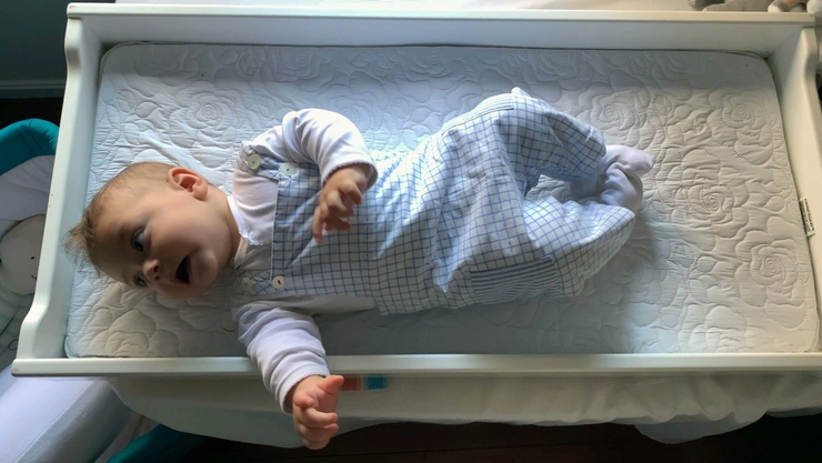 bebelus care sta pe un pat