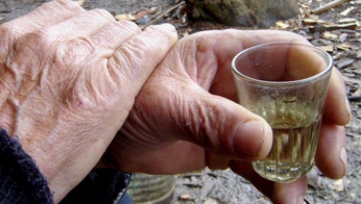 un pahar de țuică în mâna unui bătrân