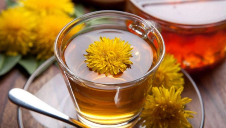 o cana cu ceai din plante pe o masa langa un ceainic