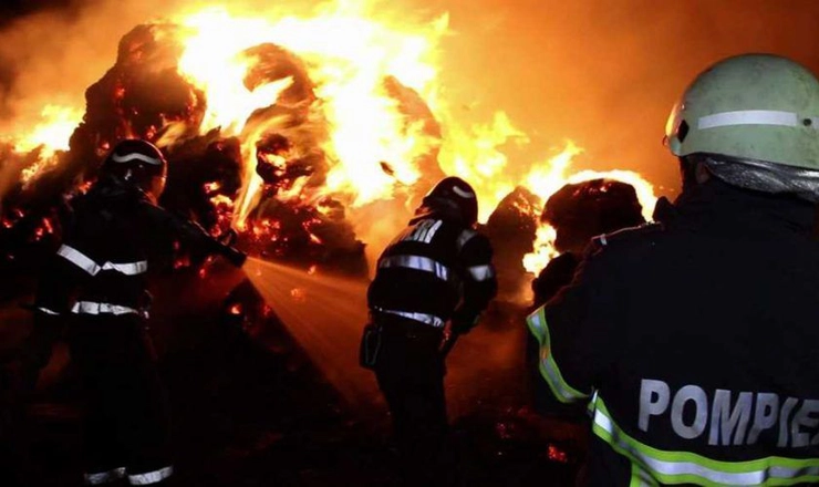  pompieri stingand un incendiu