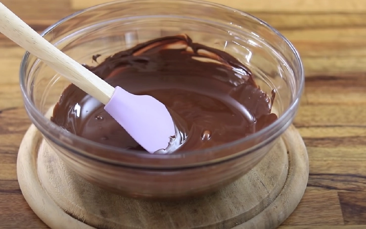o lingura intr-un bol cu glazura de ciocolata cu frisca