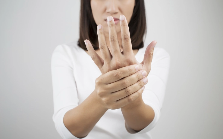 femeie care se tine de mana din cauza lipsei de calciu