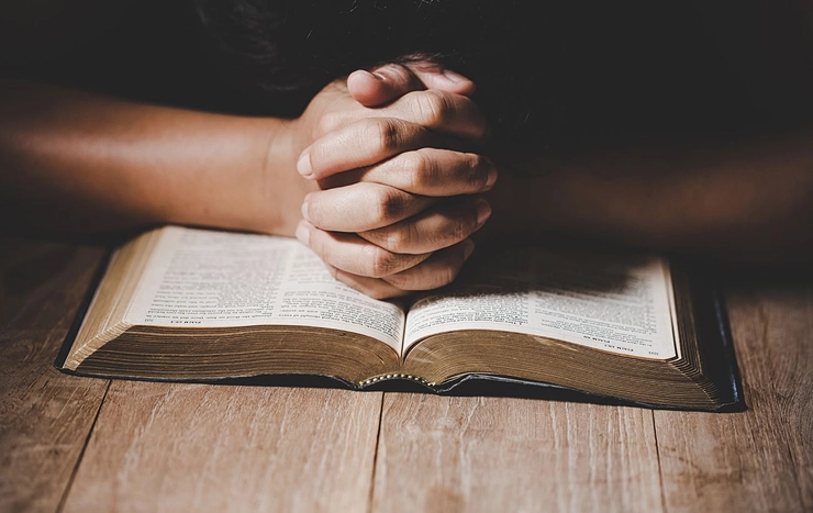 persoana care se roaga in fata bibliei pentru noroc
