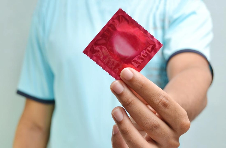 persoana ce tine in mana un prezervativ