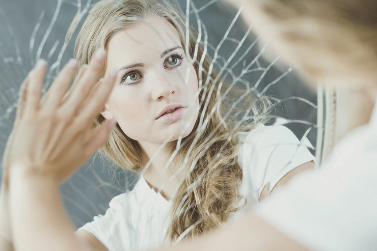 femeie în fata unei oglinzi sparte