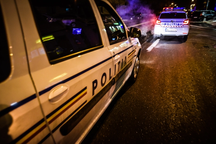 Doua masini de Politie circula noaptea pe o strada 