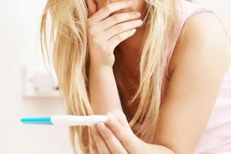 femeie care tine in mana un test de sarcina