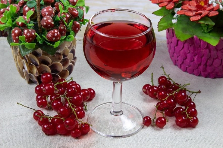 un pahar cu vin de casa langa mai multe fructe pe o masa