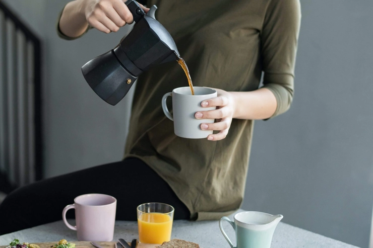 o persoană care toarnă cafea într-o cană