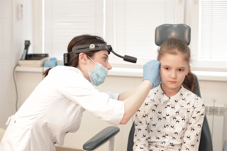 medic care efectueaza un cotrol a urechii unui copil