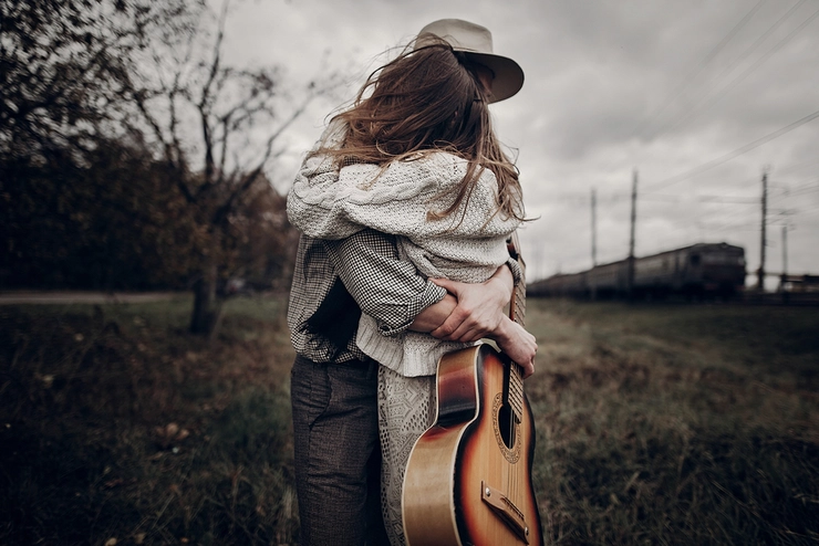 un barbat cu o chitara in mana care imbratiseaza o fata