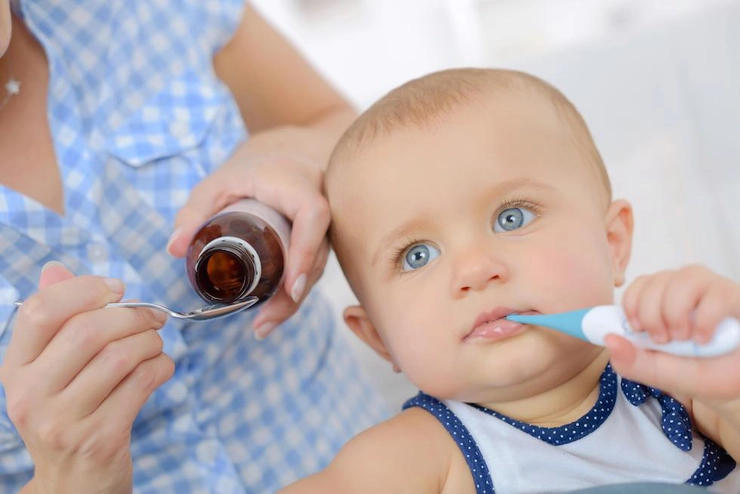 bebeluș cu ochi albaștri care are un termometru în gură