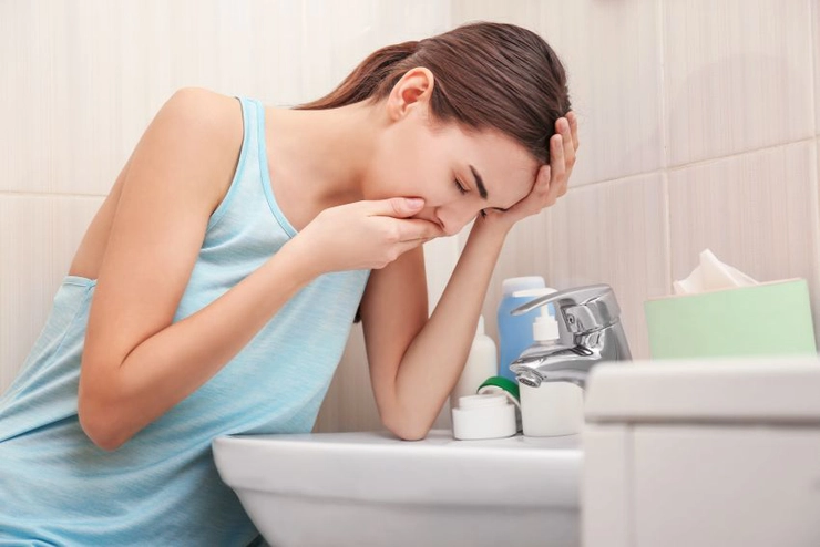 o femeie cu senzație de greață în fața unei toalete