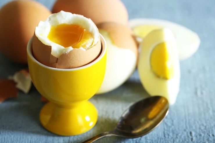 un ou fiert pe un suport langa alte oua fierte si o lingurita