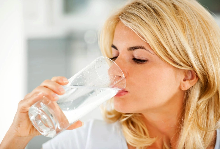 femeie care bea apa din pahar