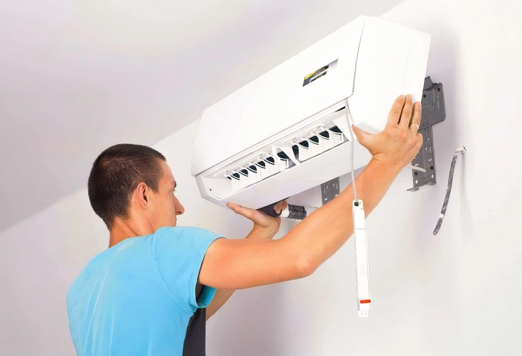 o poză cu un instalator ce montează un aparat de aer condiționat